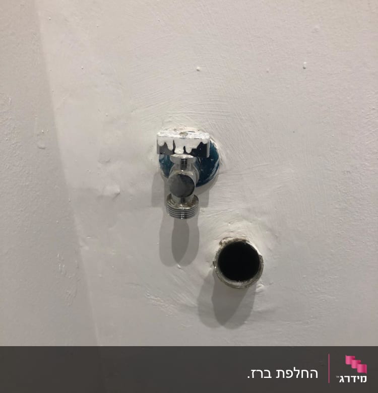 שסתום מים וצינור בקיר לבן